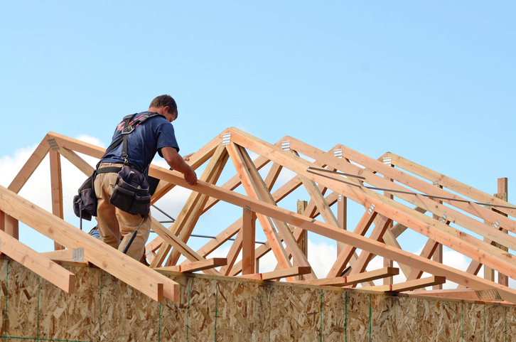 Construction worker piecing together a house frame